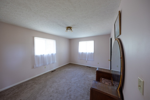 carpeted empty room with a textured ceiling