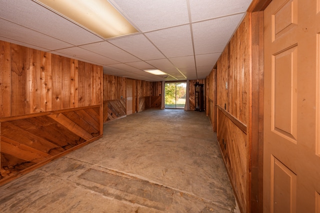 basement with a paneled ceiling and wooden walls