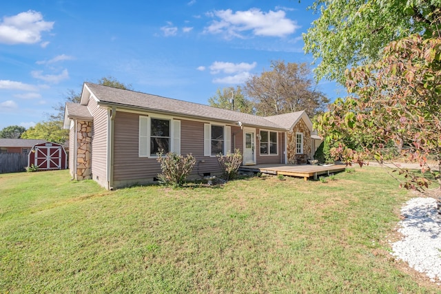 ranch-style house with a storage unit, a deck, and a front yard