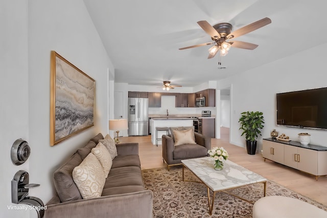 living room featuring ceiling fan, sink, and light hardwood / wood-style flooring