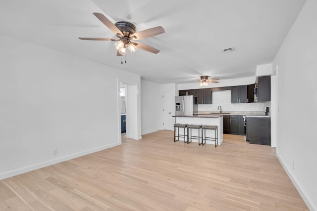 kitchen with a kitchen breakfast bar, stainless steel appliances, sink, a center island, and light hardwood / wood-style floors