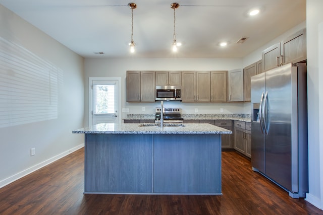 kitchen featuring hanging light fixtures, appliances with stainless steel finishes, dark hardwood / wood-style floors, and a kitchen island with sink