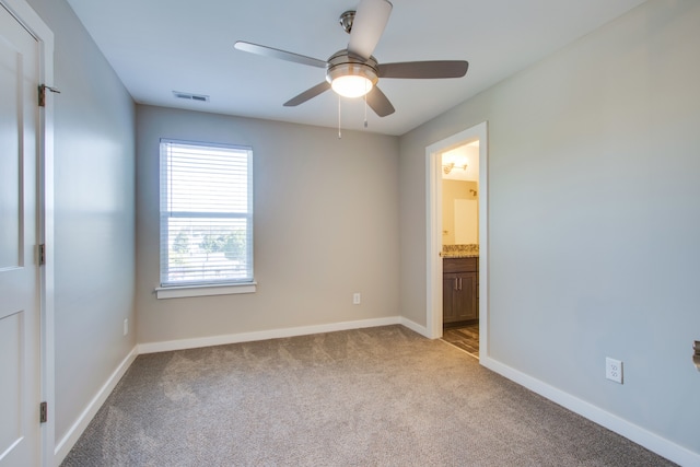 unfurnished bedroom with ensuite bath, light carpet, and ceiling fan