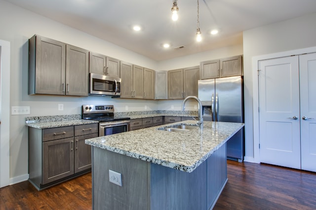 kitchen with stainless steel appliances, dark wood-type flooring, sink, and an island with sink