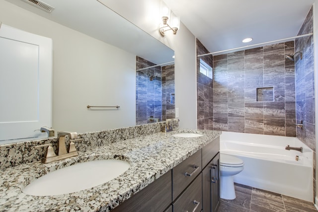 full bathroom with tiled shower / bath, vanity, and toilet