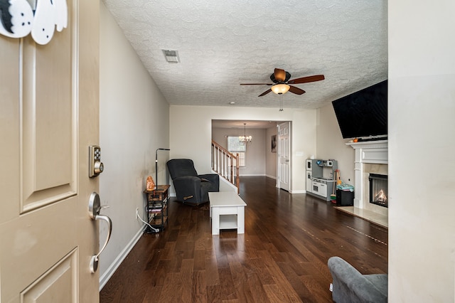 living room with dark hardwood / wood-style floors, a textured ceiling, and ceiling fan with notable chandelier