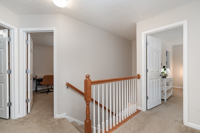 hallway with light carpet and a textured ceiling