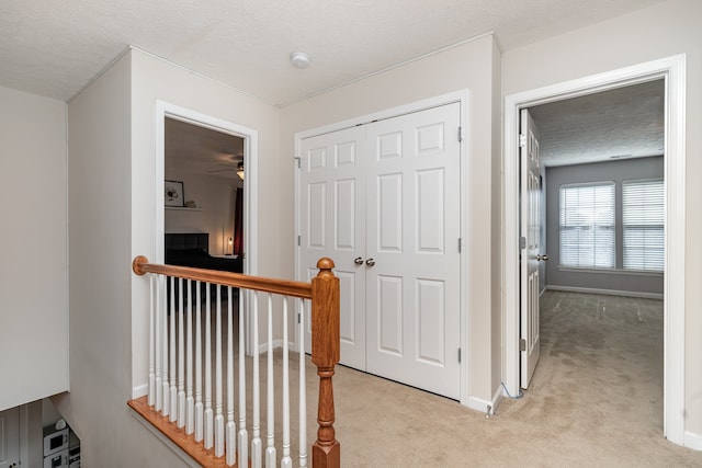 hallway with light carpet and a textured ceiling