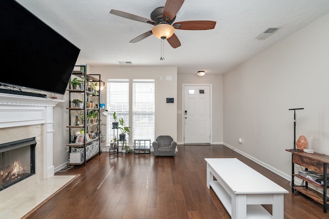 living room featuring a high end fireplace, ceiling fan, a textured ceiling, and dark hardwood / wood-style floors