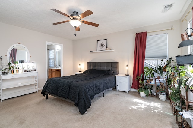 carpeted bedroom featuring ensuite bath, a textured ceiling, and ceiling fan