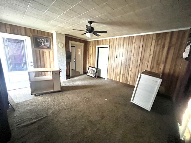 empty room featuring dark carpet, wooden walls, and ceiling fan