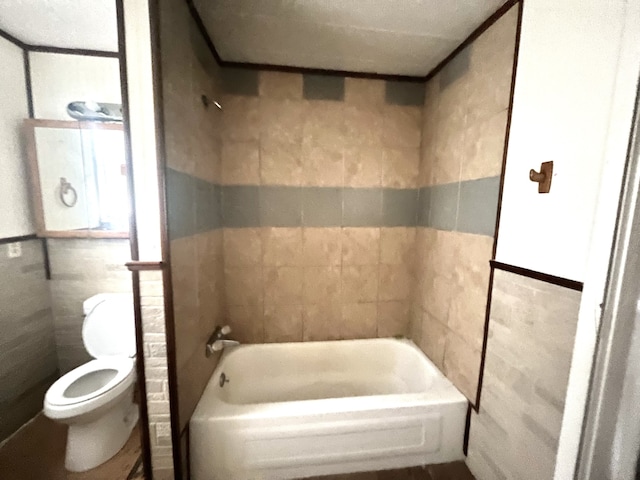 bathroom with toilet, tile walls, and shower / bath combination