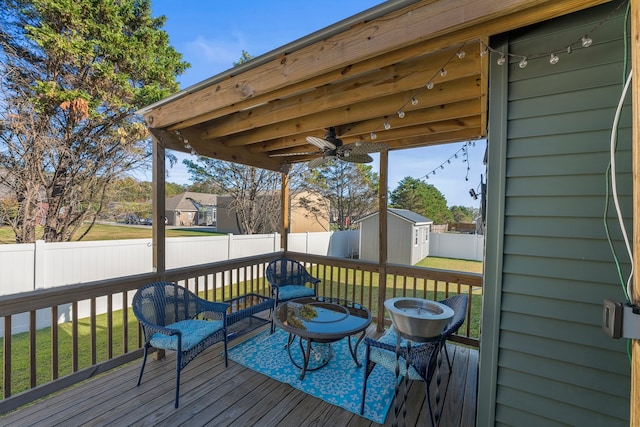 deck featuring a shed, a yard, and ceiling fan