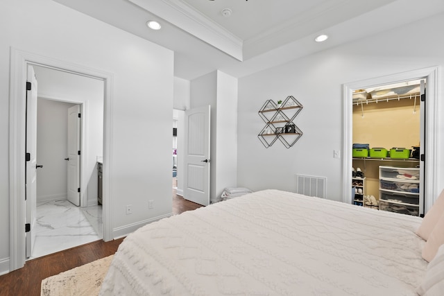 bedroom with a spacious closet, a closet, connected bathroom, ornamental molding, and dark hardwood / wood-style floors