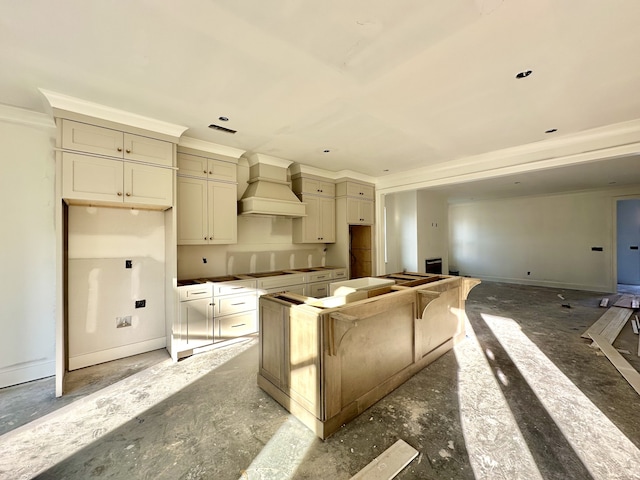 kitchen featuring a kitchen island, crown molding, premium range hood, and cream cabinets