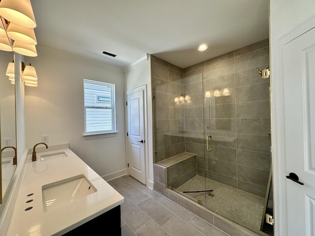 bathroom featuring double vanity, a sink, a shower stall, baseboards, and tile patterned floors