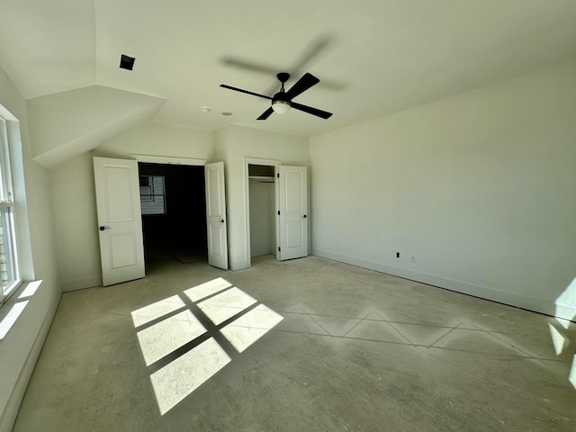 unfurnished bedroom with vaulted ceiling, concrete floors, baseboards, and ceiling fan