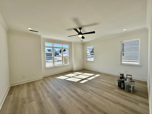 spare room with baseboards, a ceiling fan, ornamental molding, light wood-style floors, and recessed lighting