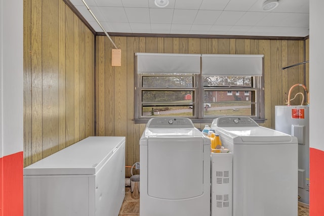 laundry room with independent washer and dryer, electric water heater, and wooden walls