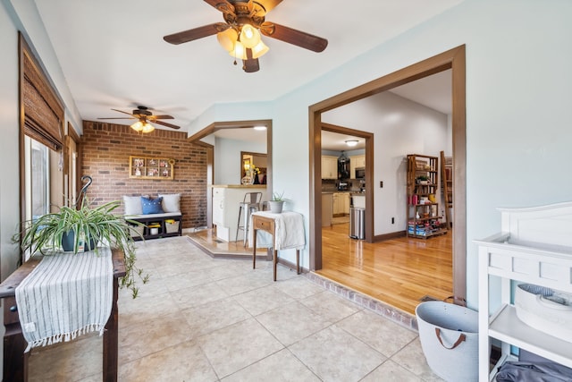 living room featuring brick wall, light hardwood / wood-style floors, and ceiling fan