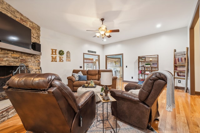 living room with light hardwood / wood-style floors, a fireplace, and ceiling fan