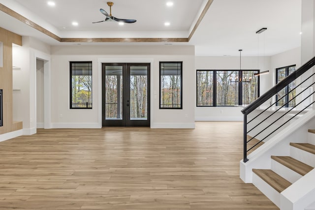 foyer with french doors, light hardwood / wood-style flooring, a tray ceiling, and a chandelier