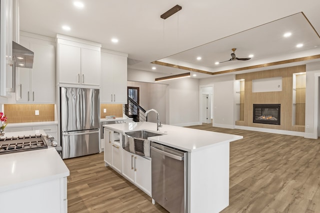 kitchen with stainless steel appliances, white cabinetry, a kitchen island with sink, and sink