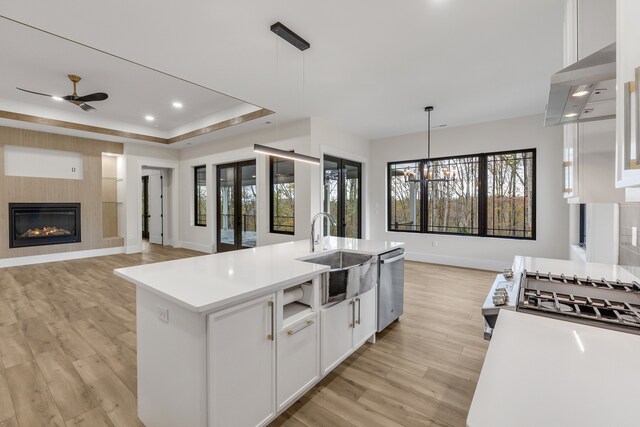 kitchen with ceiling fan with notable chandelier, a large fireplace, extractor fan, decorative light fixtures, and white cabinets