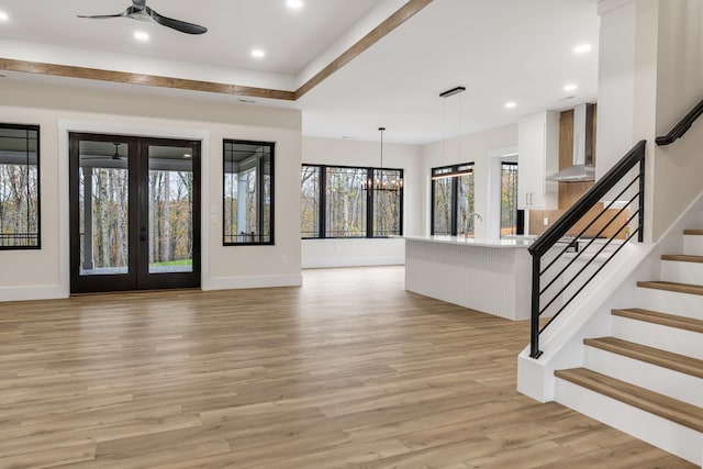 foyer entrance with french doors, light hardwood / wood-style floors, and ceiling fan with notable chandelier