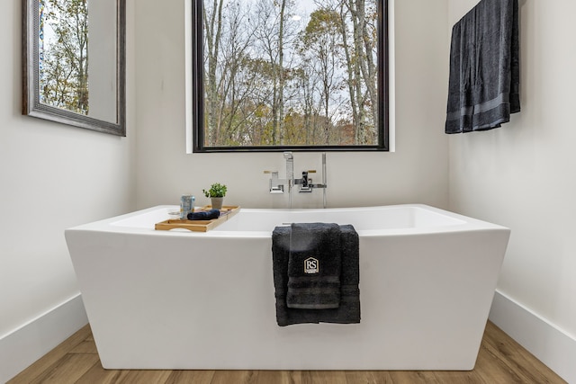 bathroom with hardwood / wood-style flooring and a bath