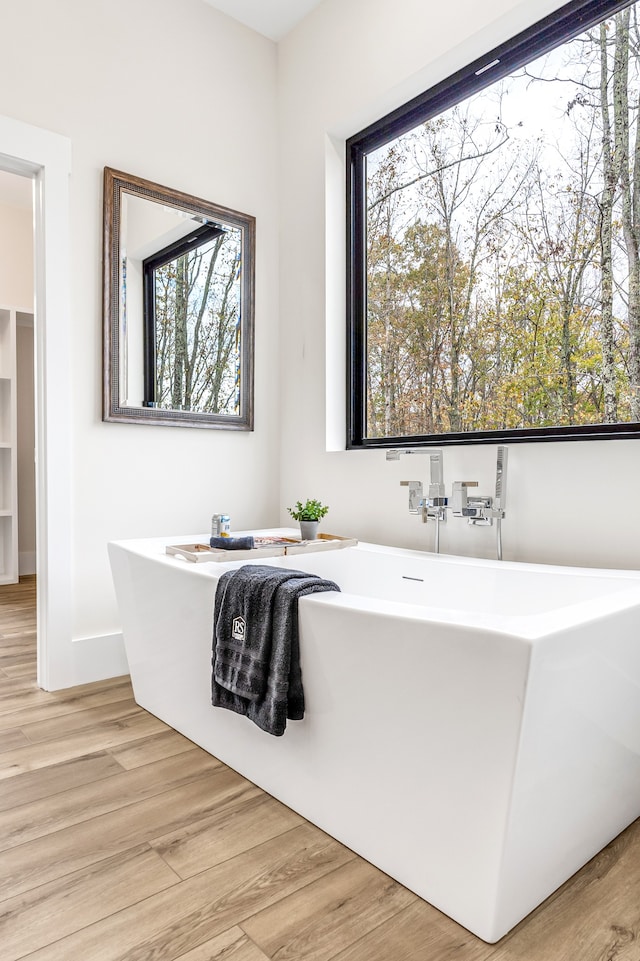 bathroom with a washtub and hardwood / wood-style flooring