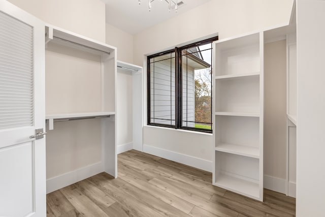 walk in closet featuring light hardwood / wood-style flooring and an inviting chandelier