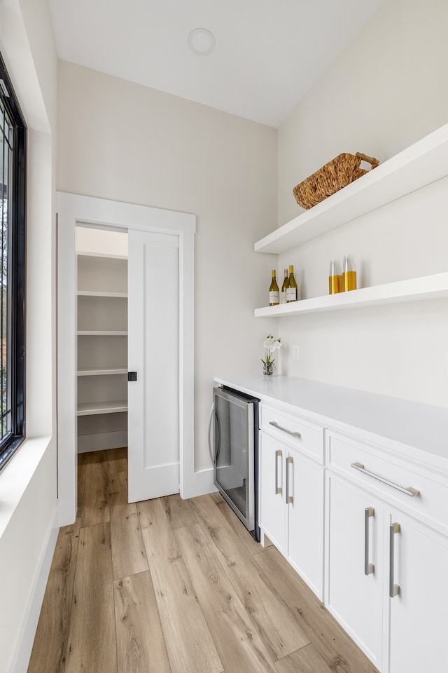 bar featuring white cabinets, beverage cooler, and light hardwood / wood-style flooring