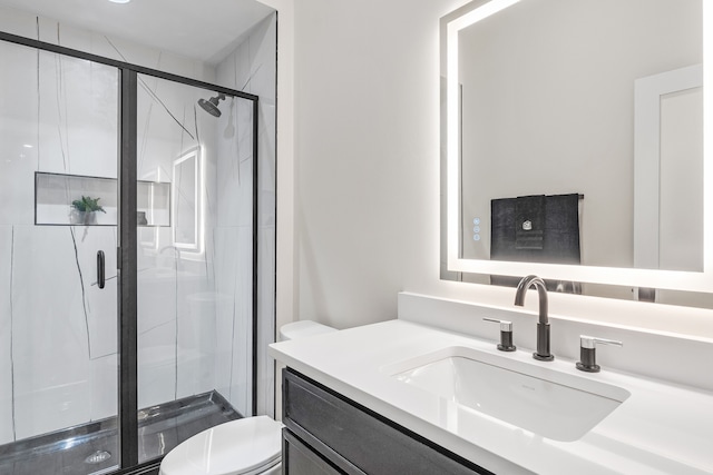 bathroom featuring a shower with door, vanity, and toilet