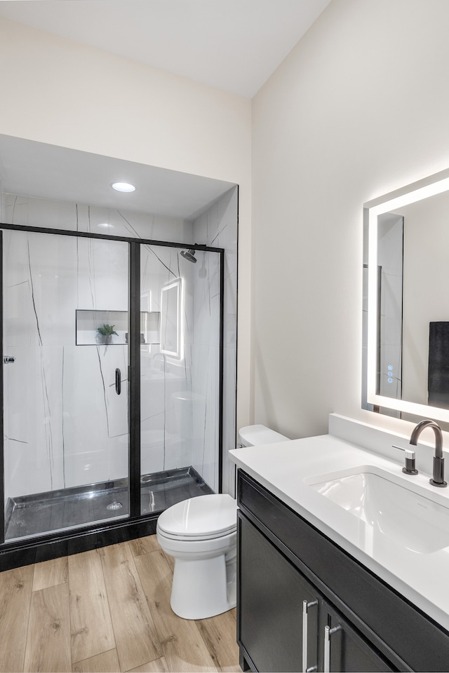 bathroom with vanity, toilet, and a shower with door