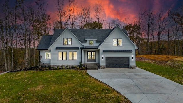 modern inspired farmhouse with a garage and a lawn