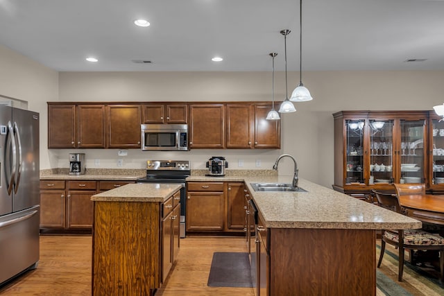 kitchen with sink, stainless steel appliances, a center island, and hanging light fixtures