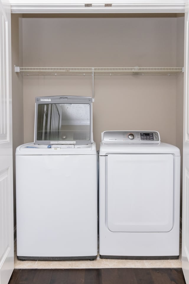 laundry area with washer and dryer and dark wood-type flooring