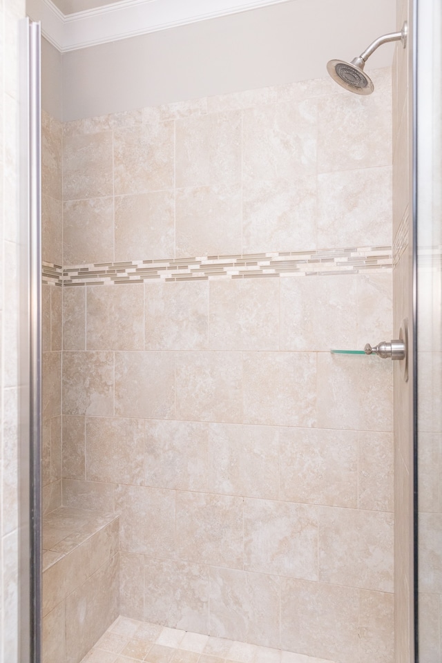 bathroom with a shower with door and crown molding