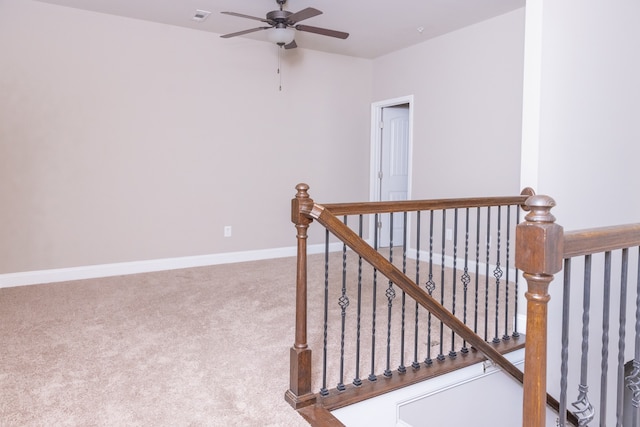 staircase with ceiling fan and carpet