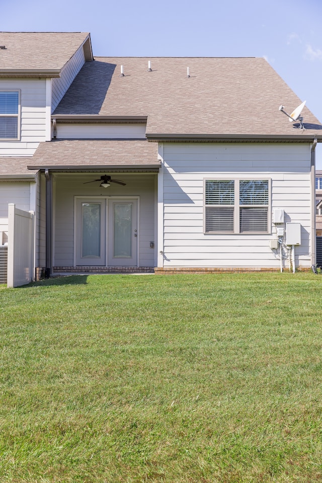 rear view of property featuring a yard and ceiling fan