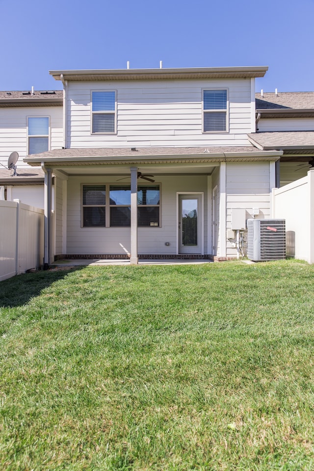 rear view of house with central air condition unit and a lawn