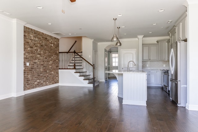 kitchen with dark wood-type flooring, stainless steel appliances, a breakfast bar area, and a center island with sink