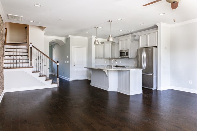 kitchen featuring a kitchen bar, hanging light fixtures, stainless steel appliances, dark wood-type flooring, and ornamental molding