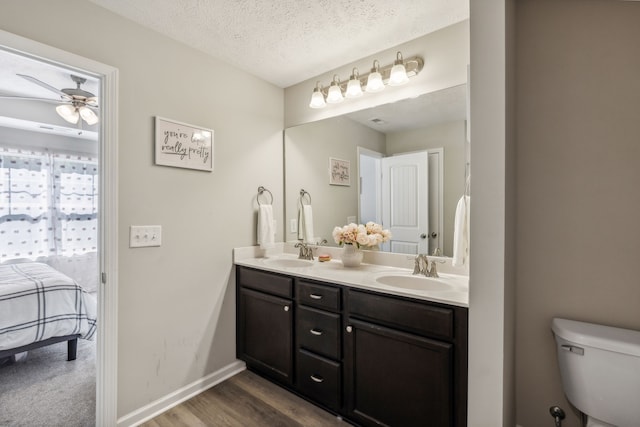 bathroom with hardwood / wood-style floors, ceiling fan, a textured ceiling, toilet, and vanity