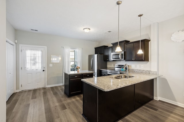 kitchen with hardwood / wood-style flooring, kitchen peninsula, sink, pendant lighting, and appliances with stainless steel finishes