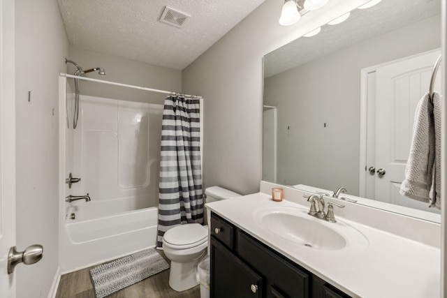 full bathroom featuring wood-type flooring, a textured ceiling, shower / bath combo, toilet, and vanity