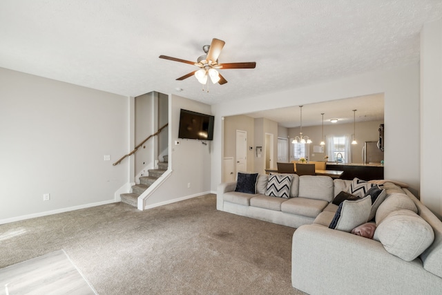 living room with carpet flooring, a textured ceiling, and ceiling fan with notable chandelier