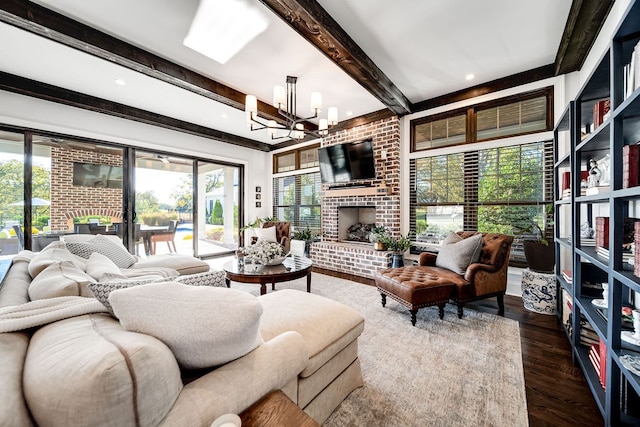 living room with dark wood-type flooring, a wealth of natural light, a chandelier, and a fireplace