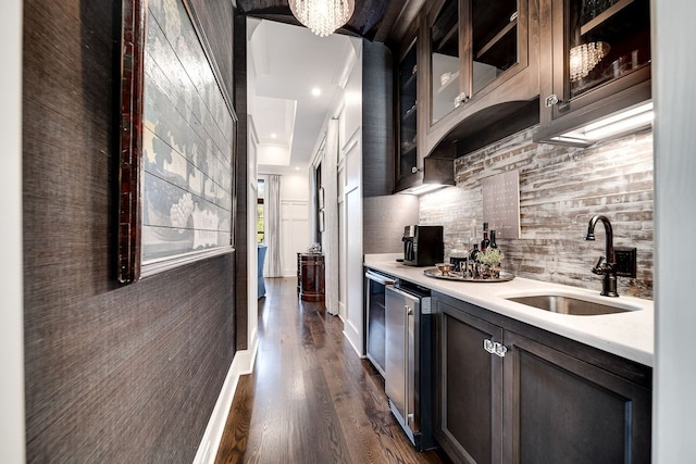 kitchen with tasteful backsplash, dark brown cabinets, dark hardwood / wood-style flooring, stainless steel refrigerator, and sink